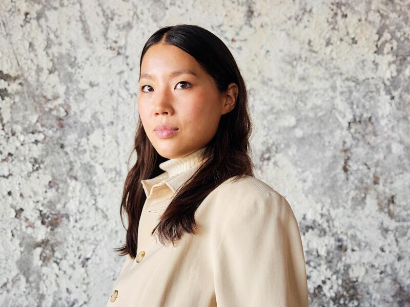 A photo of a woman standing with her arms behind her back 
