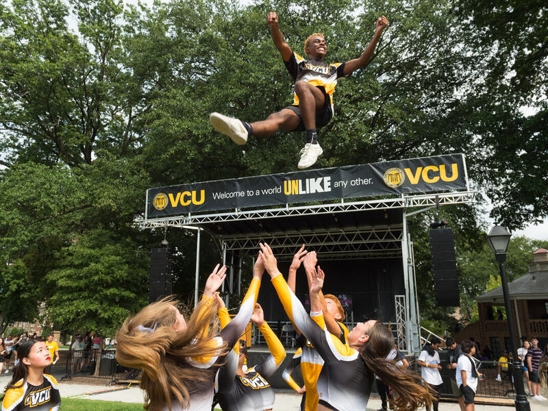 A male cheerleader being tossed into the air 