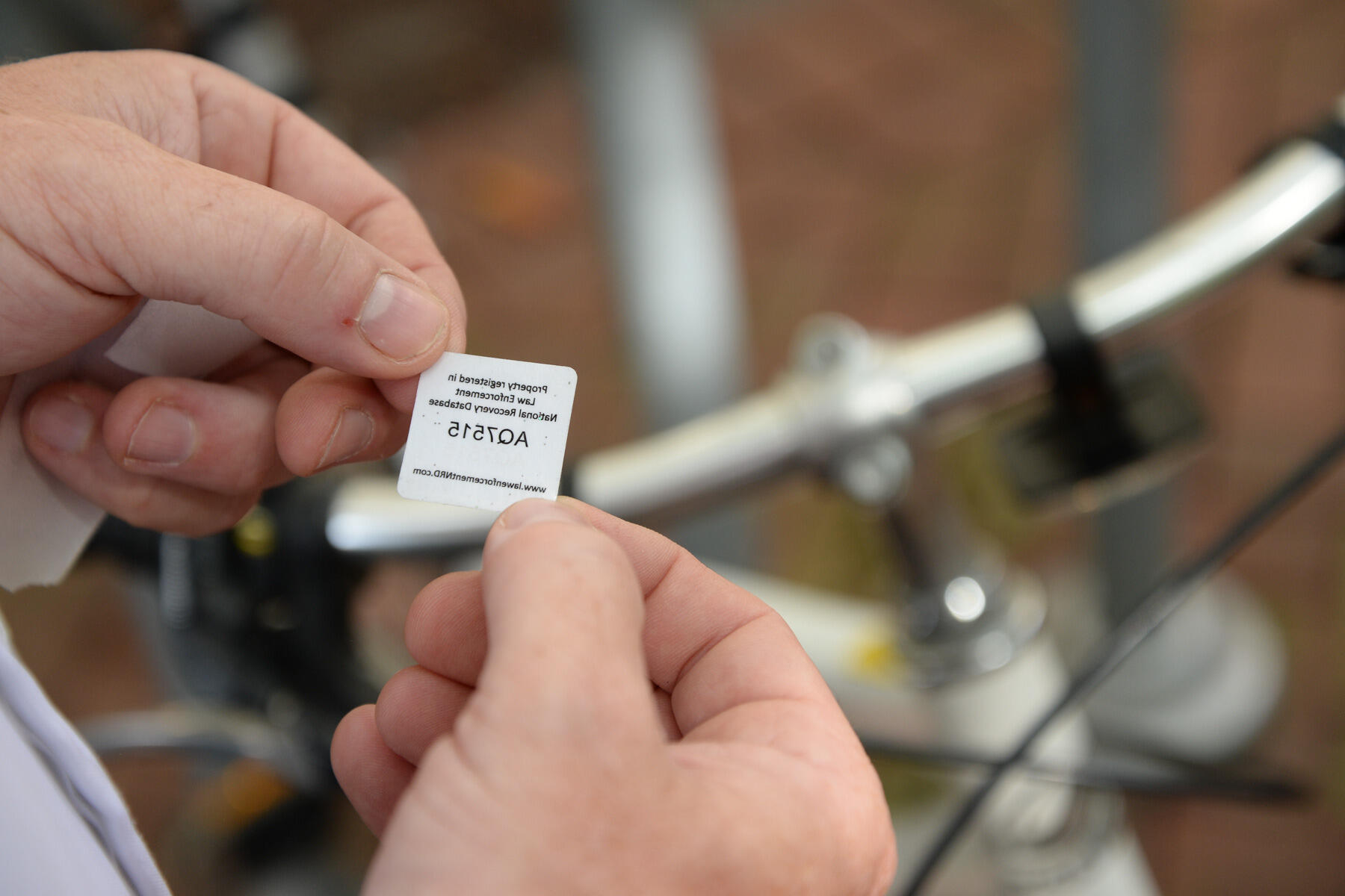 Assistant Chief of Police Chris Preuss holds a new registration sticker. The small dots are embedded with a unique, traceable serial number.