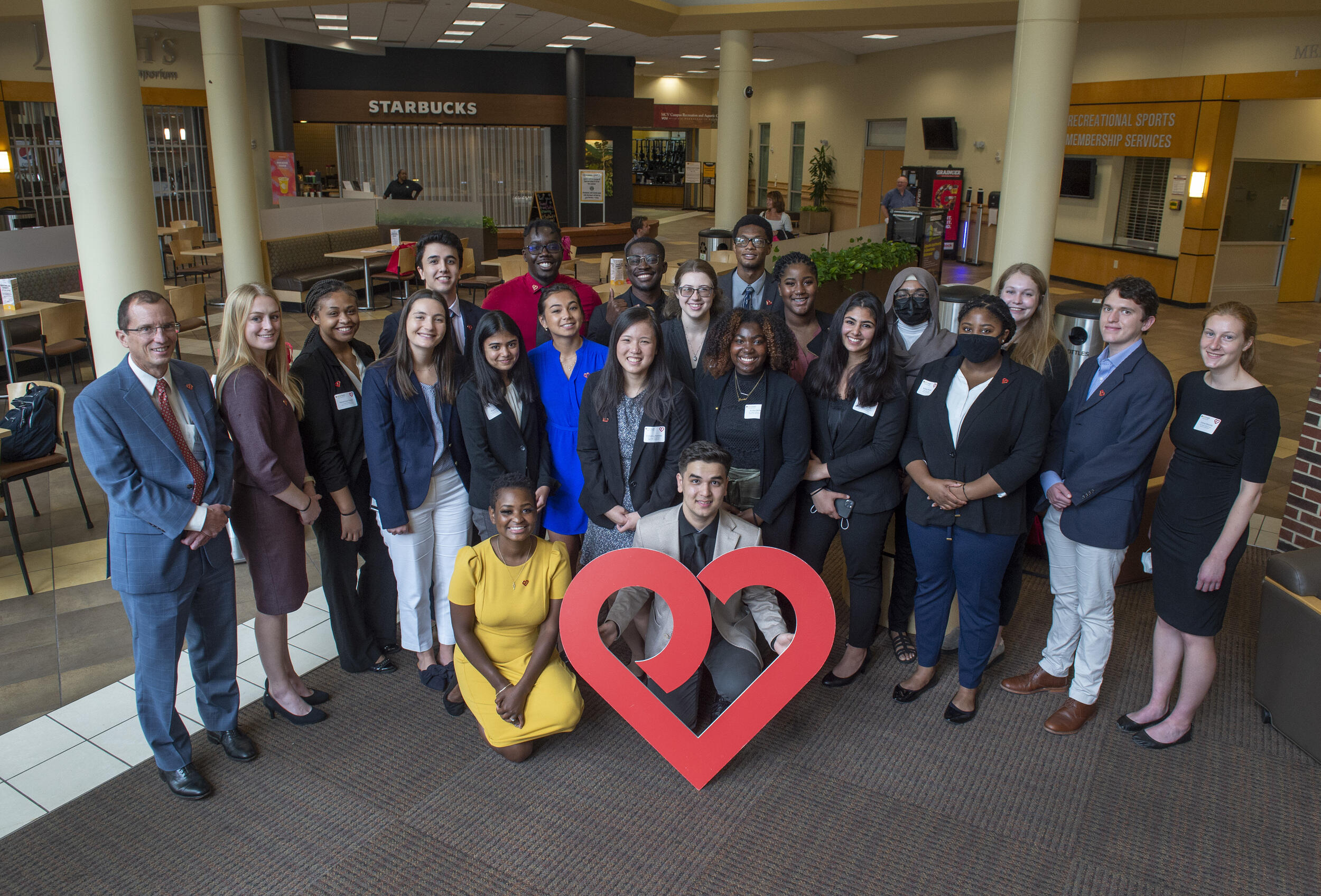 A group of people standing and sitting in front of a heart
