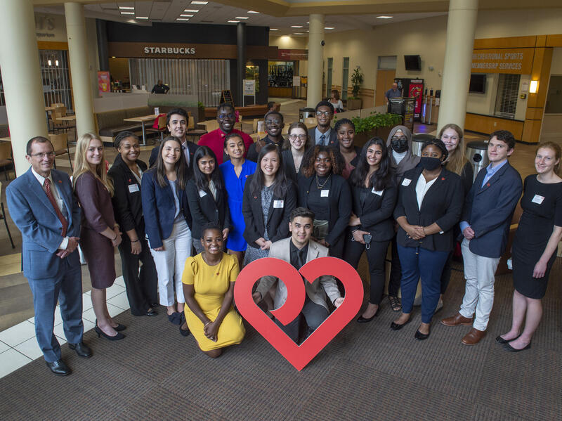 A group of people standing and sitting in front of a heart
