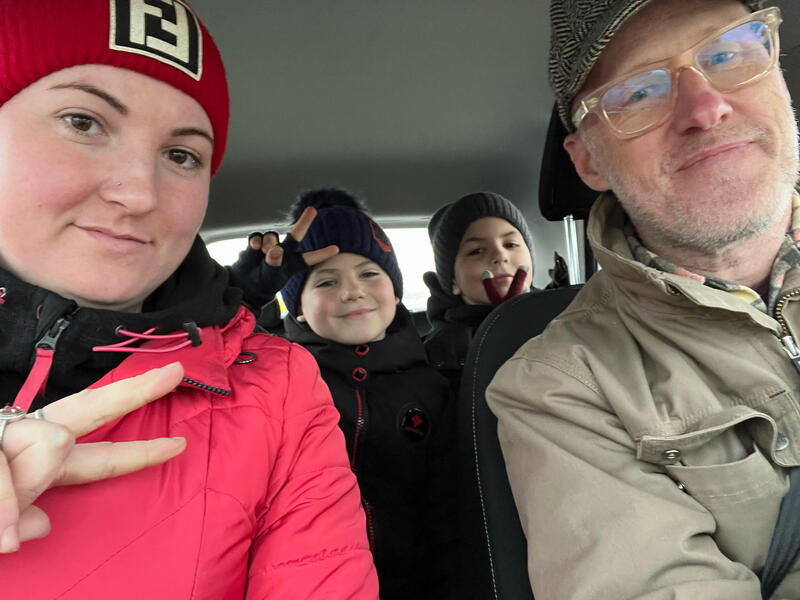 A man and woman sitting in the front of a car with two children sitting in the back. 