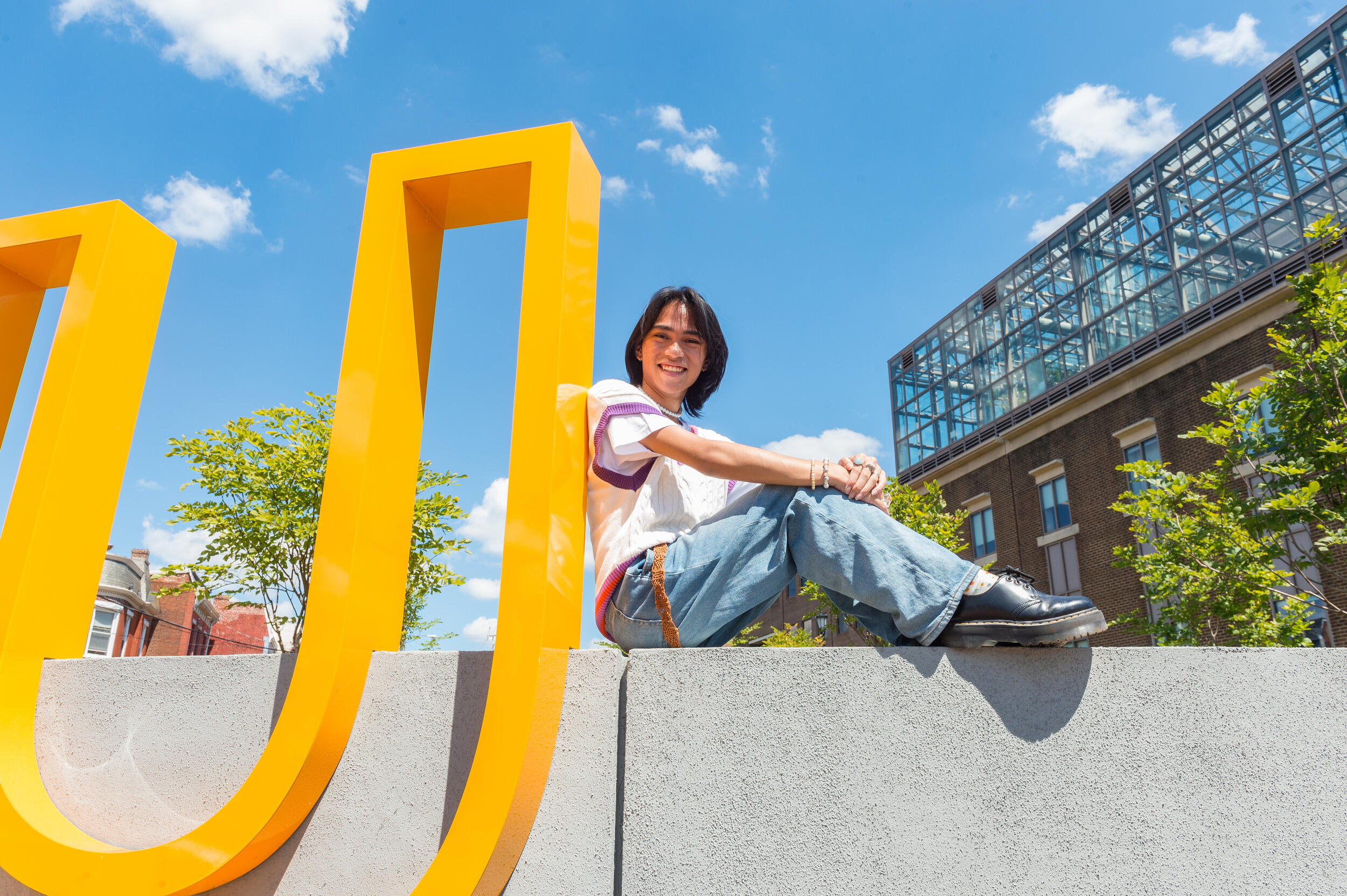 Thomas Mussomeli sitting and leaning against a giant \"U\"