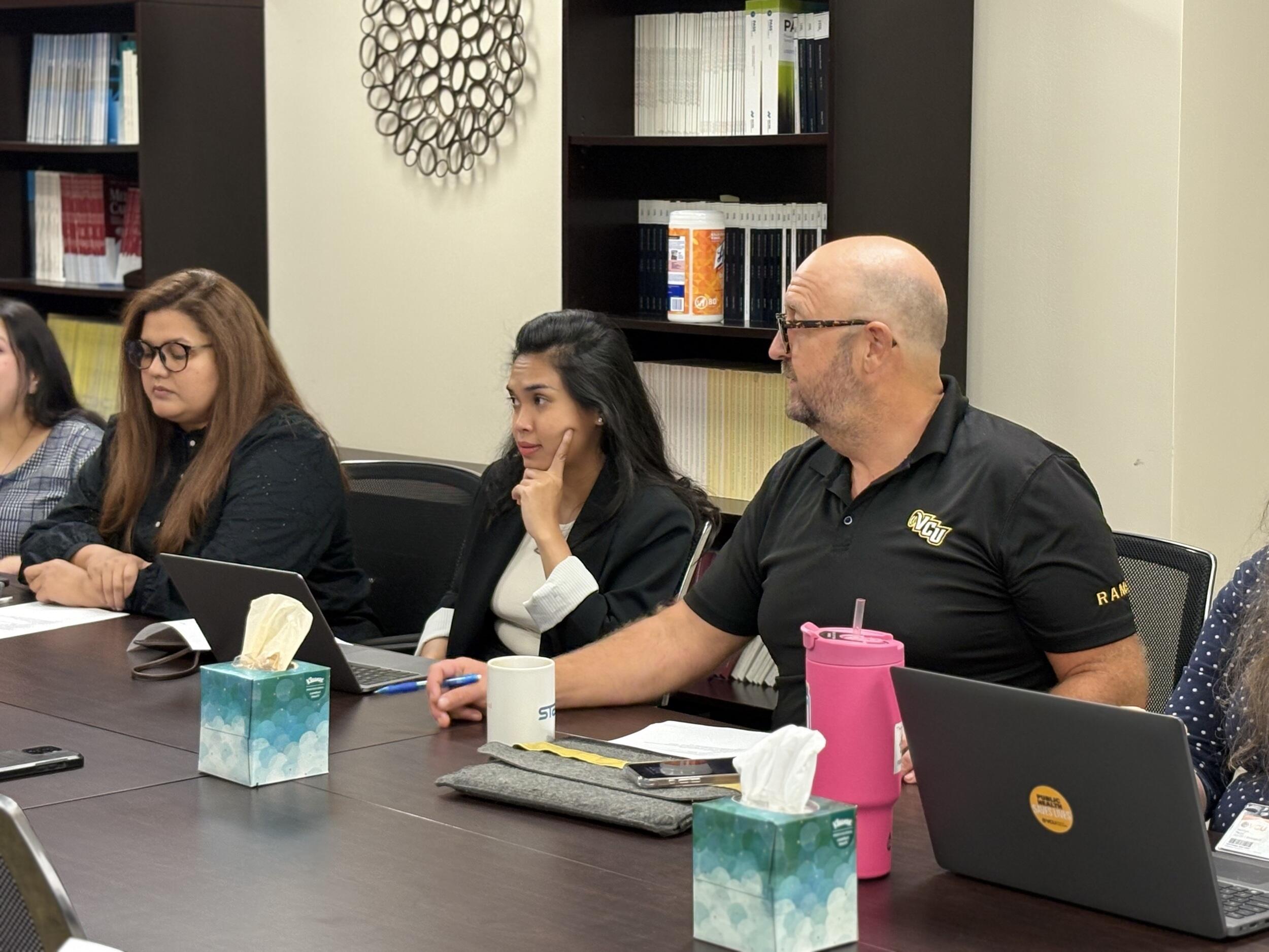 A photo of five people sitting at a table. 