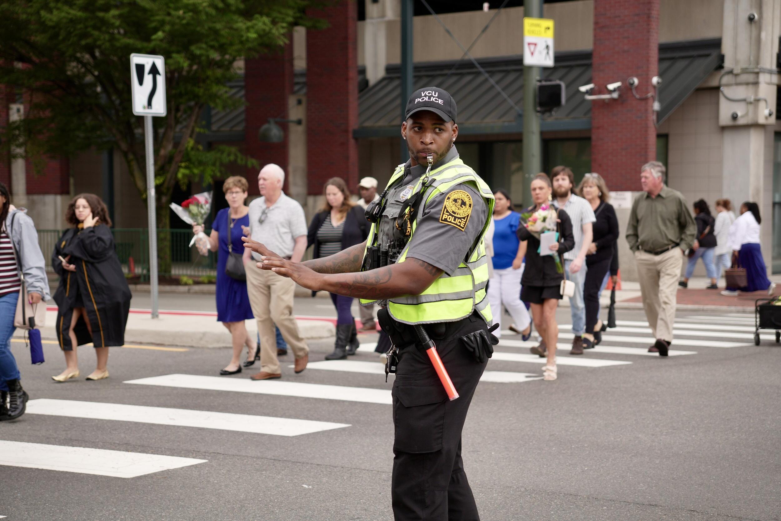 A photo of a traffic cop directing people across a cross walk. 