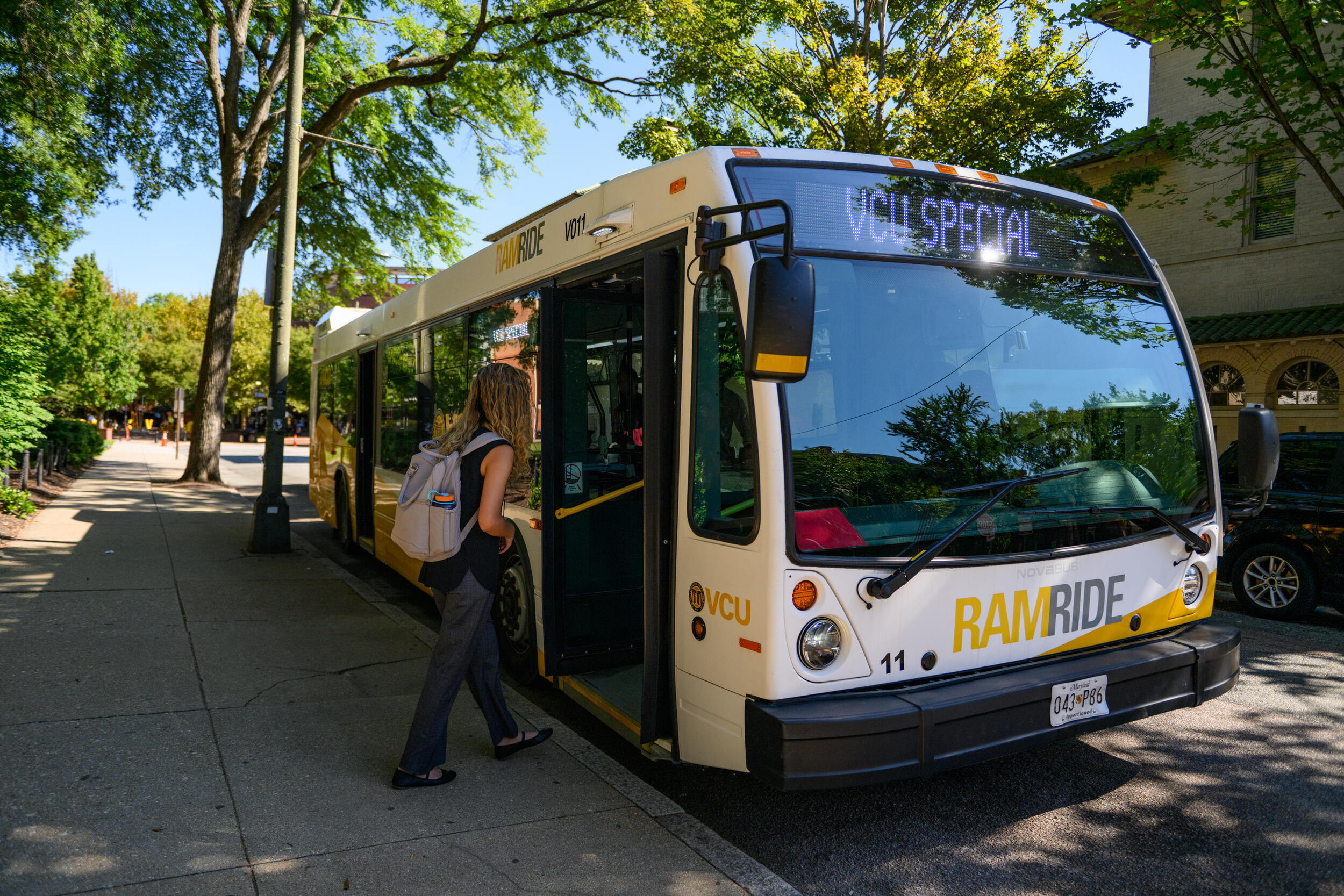 A photo of a woman walking onto a bus. The front of the bus says \"RAMRIDE\" 