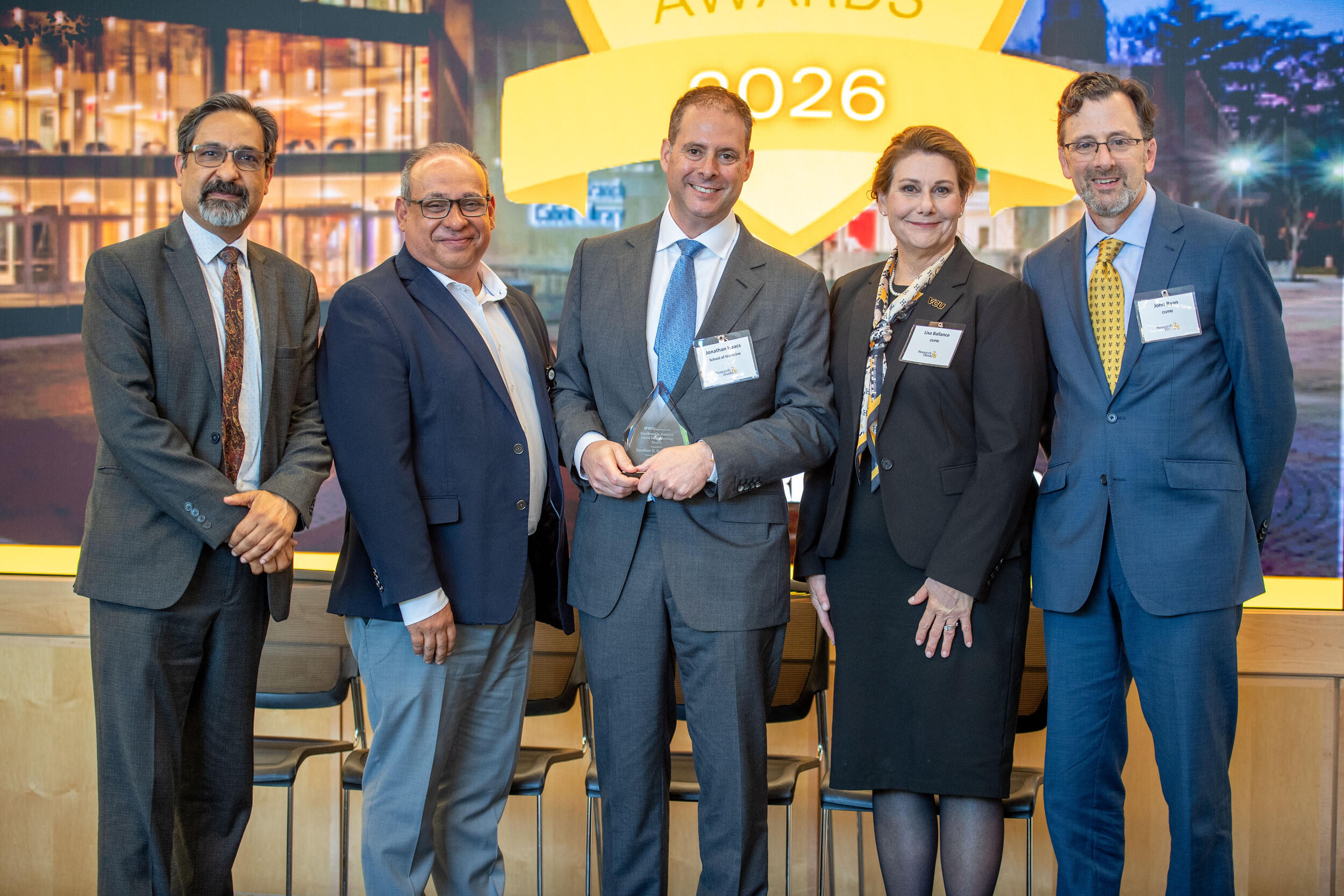 A group photo of four men and one woman. 