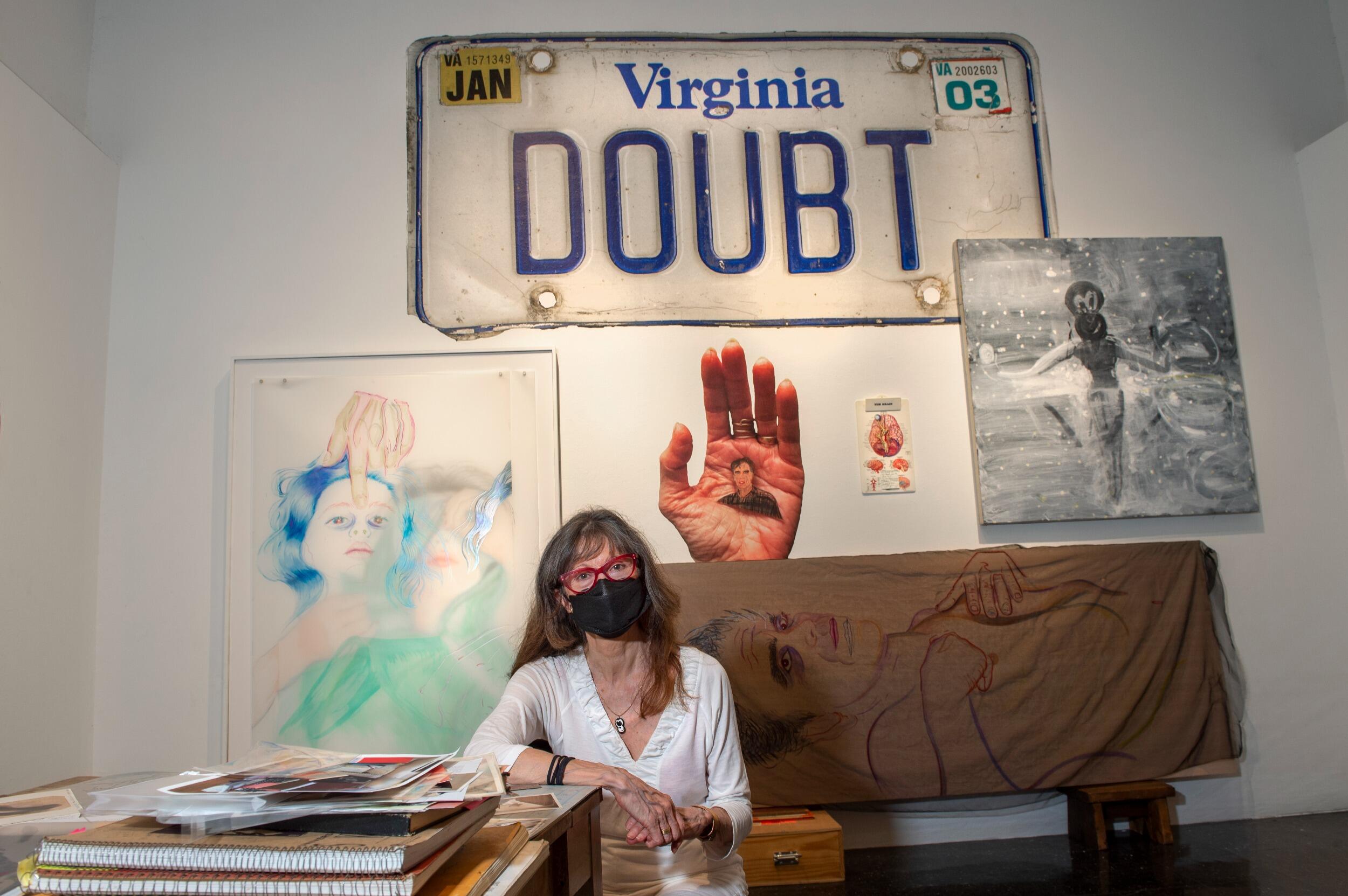 Joan Gaustad with part of The Anderson exhibition for “Someone’s Missing … and I Think It’s Me” in the background.