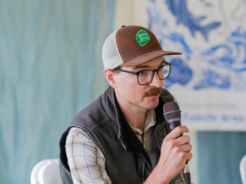 A photo of a man speaking into a microphone. 