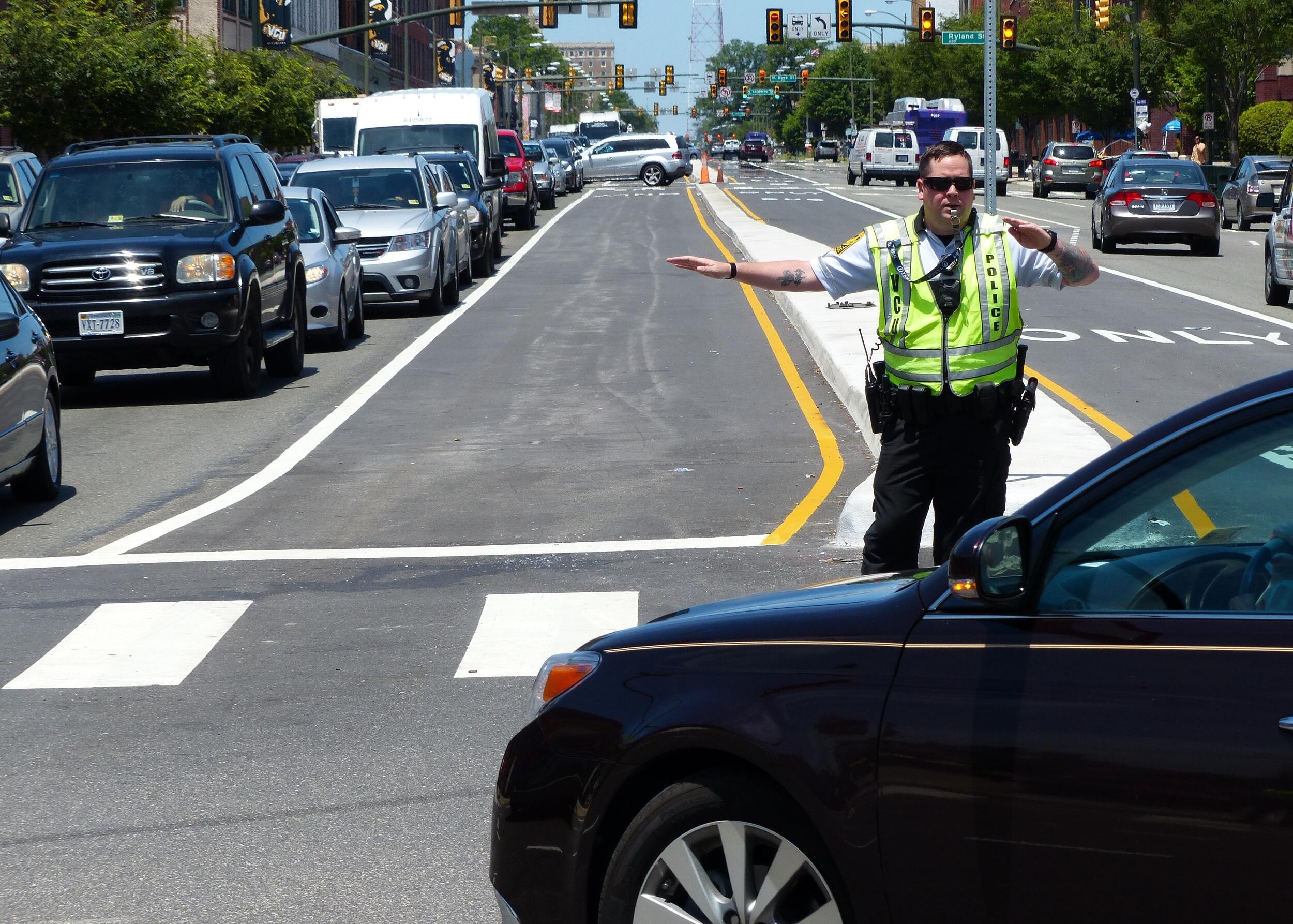 An officer in a yellow vest directs traffic.