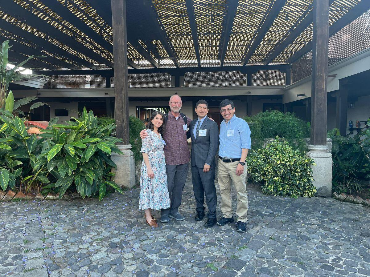 A photo of four people standing in front of a terrace with plants 