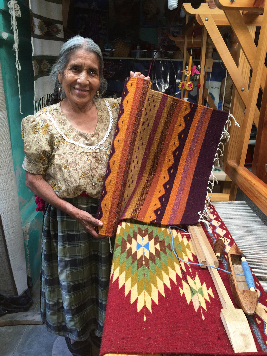 A Teotitlán del Valle craftswoman holds up the handwoven rug Cydni Gordon purchased from her as a gift to take back to her grandmother.