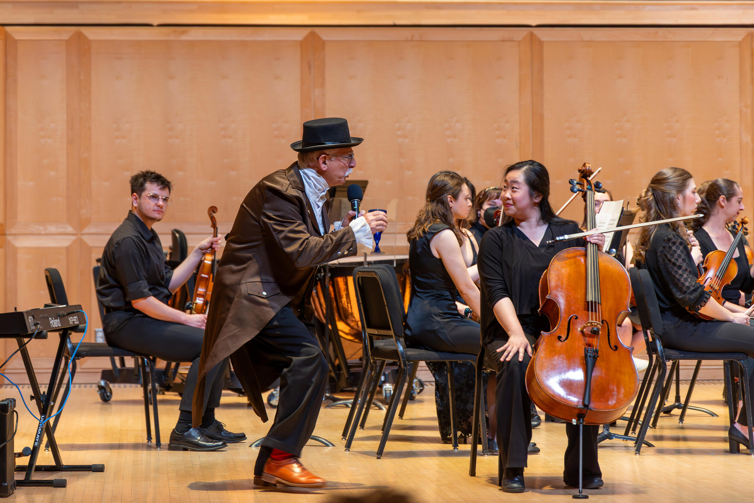 A photo of a conductor bending next to a musician in an orchestra. 