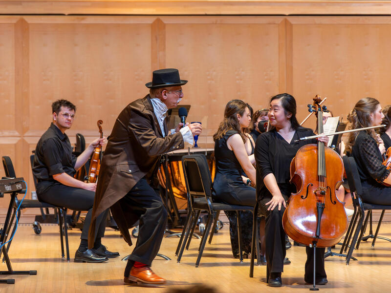 A photo of a conductor bending next to a musician in an orchestra. 