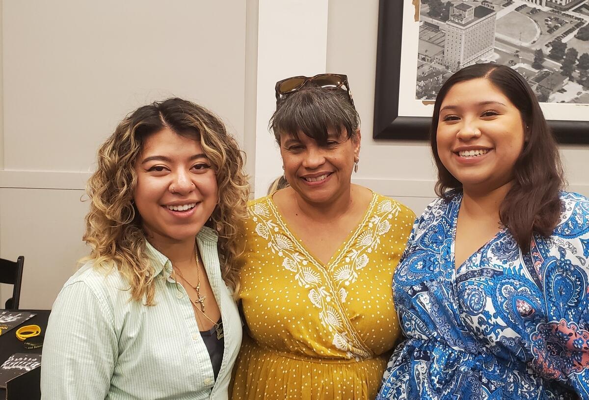Three women standing next to each other and smiling 