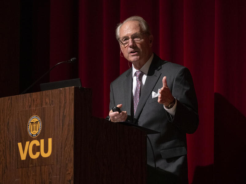 A man standing behind a podium with the VCU logo on it 