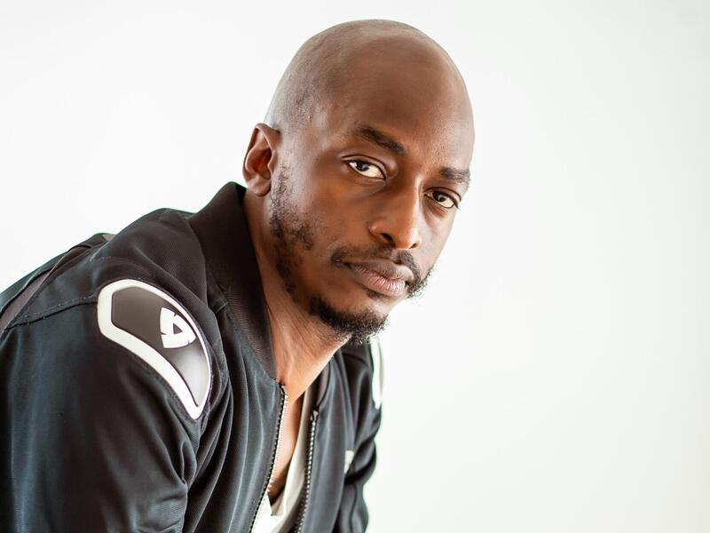 A photo of a bald man with a short beard wearing a black leather jacket. 