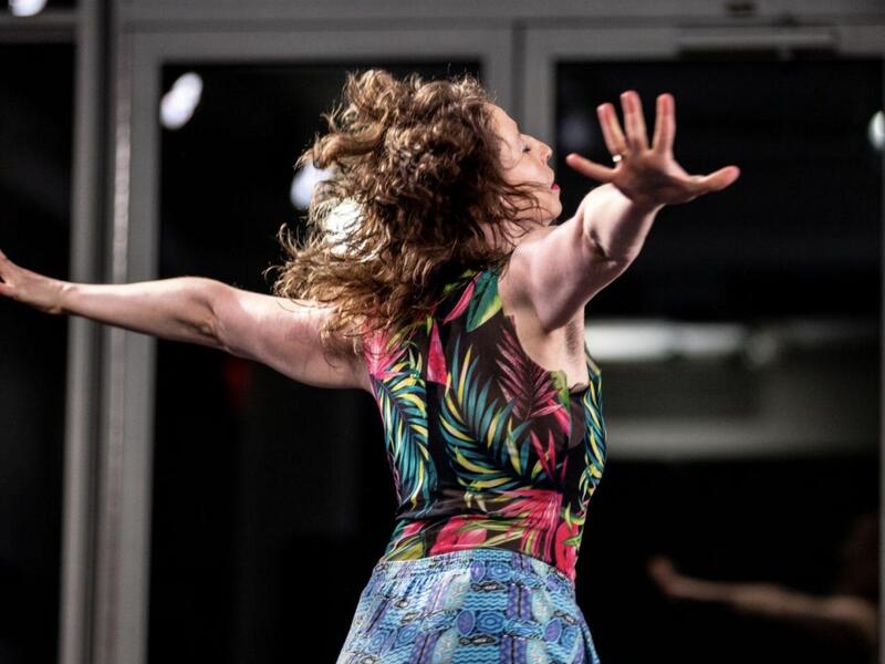 A photo of a woman dancing with her arms extended. 