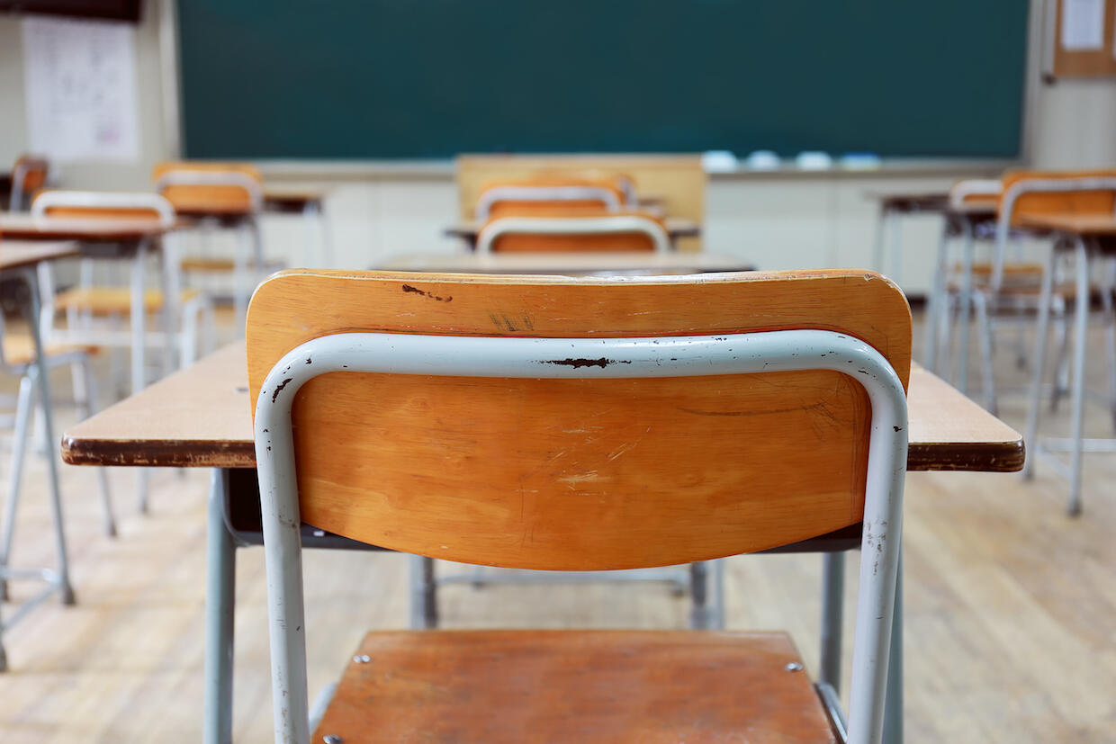 A classroom with rows of desks facing a chalkboard.
