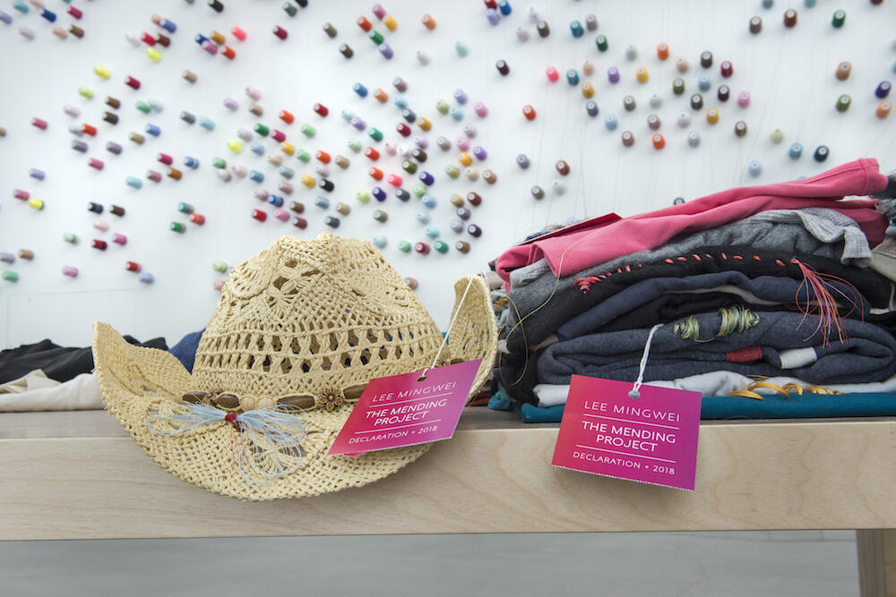 Garments that volunteers have mended at "The Mending Project" are attached to the wall with colorful spools of thread. The installation runs through Sept. 9. (Photo by Kevin Morley, University Relations)