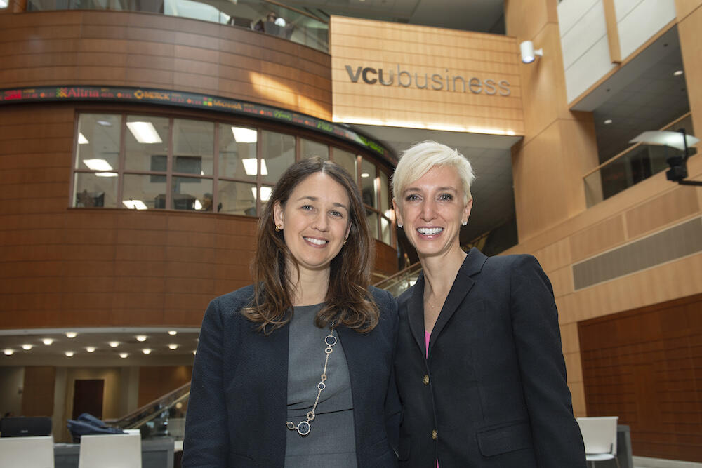 Two women stand in front of VCU Business signage. 