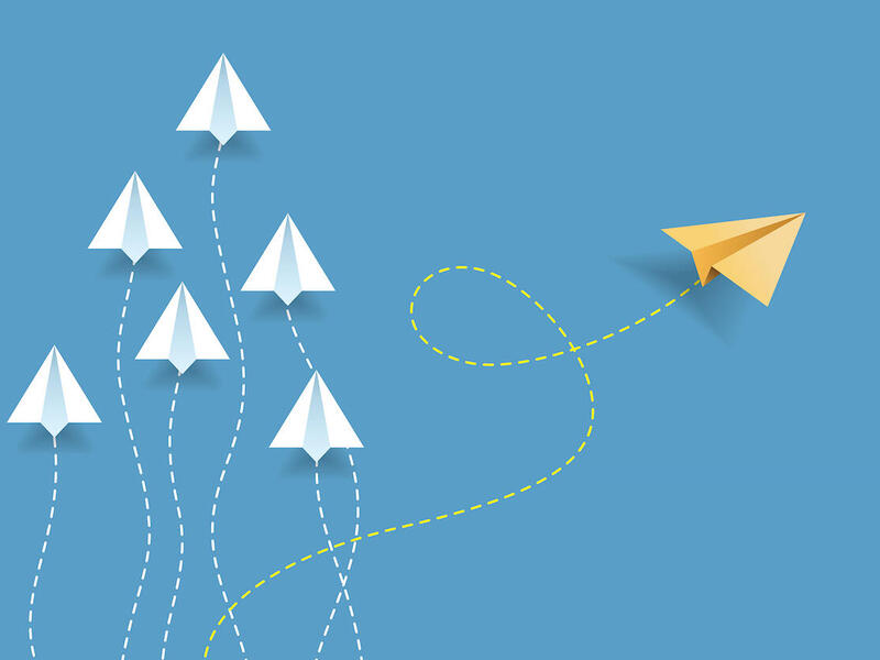 Illustration of paper airplanes with one flying off in a different direction than all the others