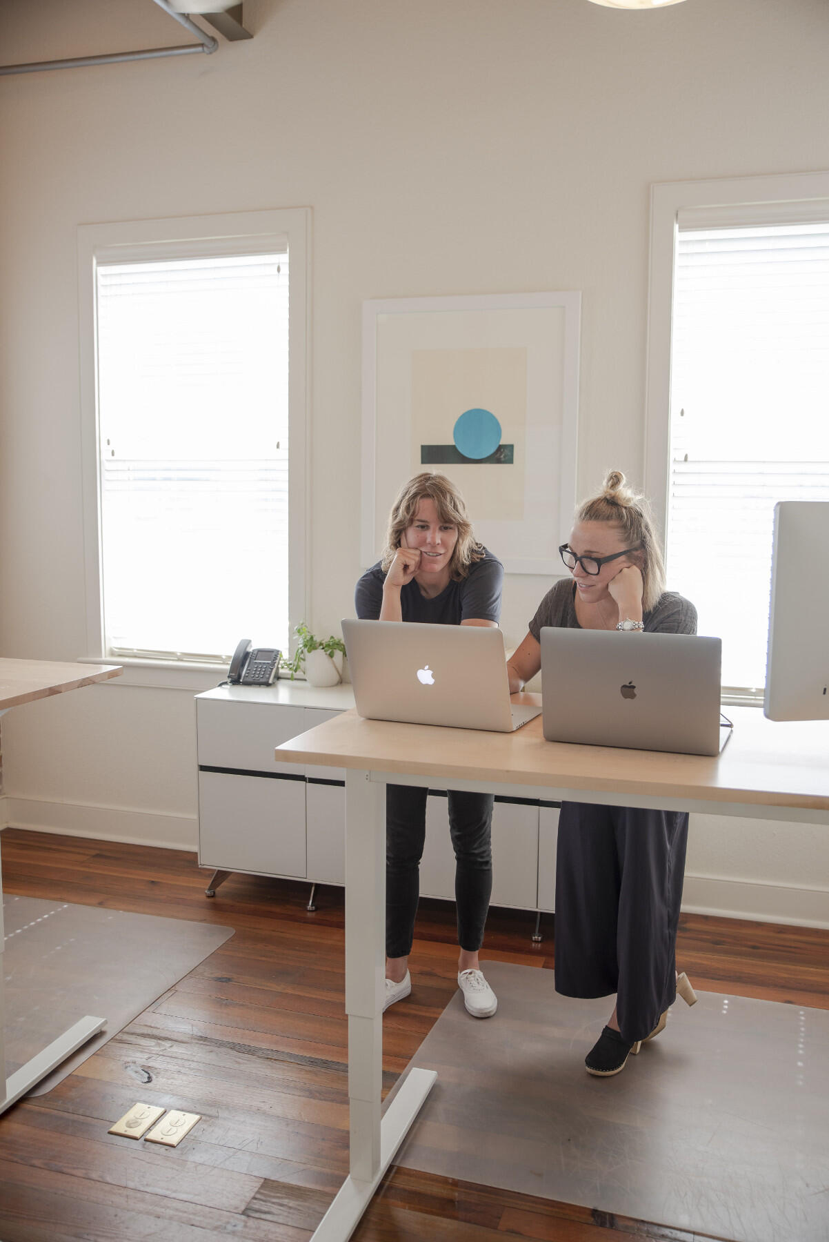 Two women standing behind a table with two laptops.