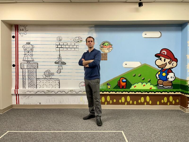 Brent Fagg standing in front of an interior mural.