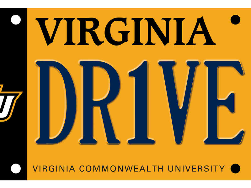 A photo of a yellow license plate that has a black strip on the left side. On top of the black strip are letter's that spell out \"VCU\" 