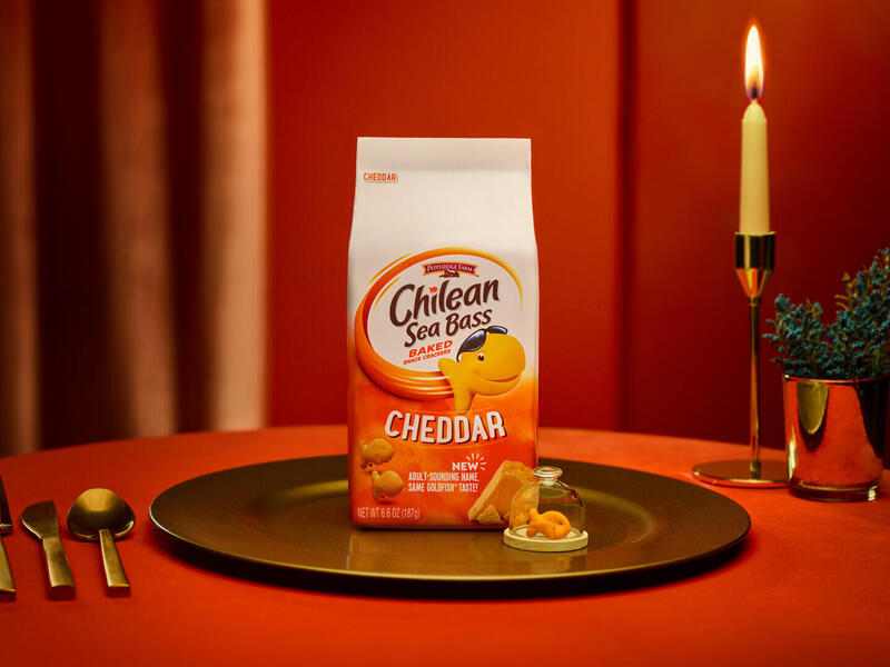 Bag with Chilean Sea Bass label is on a serving dish on a table besides utensils and a lighted candle.