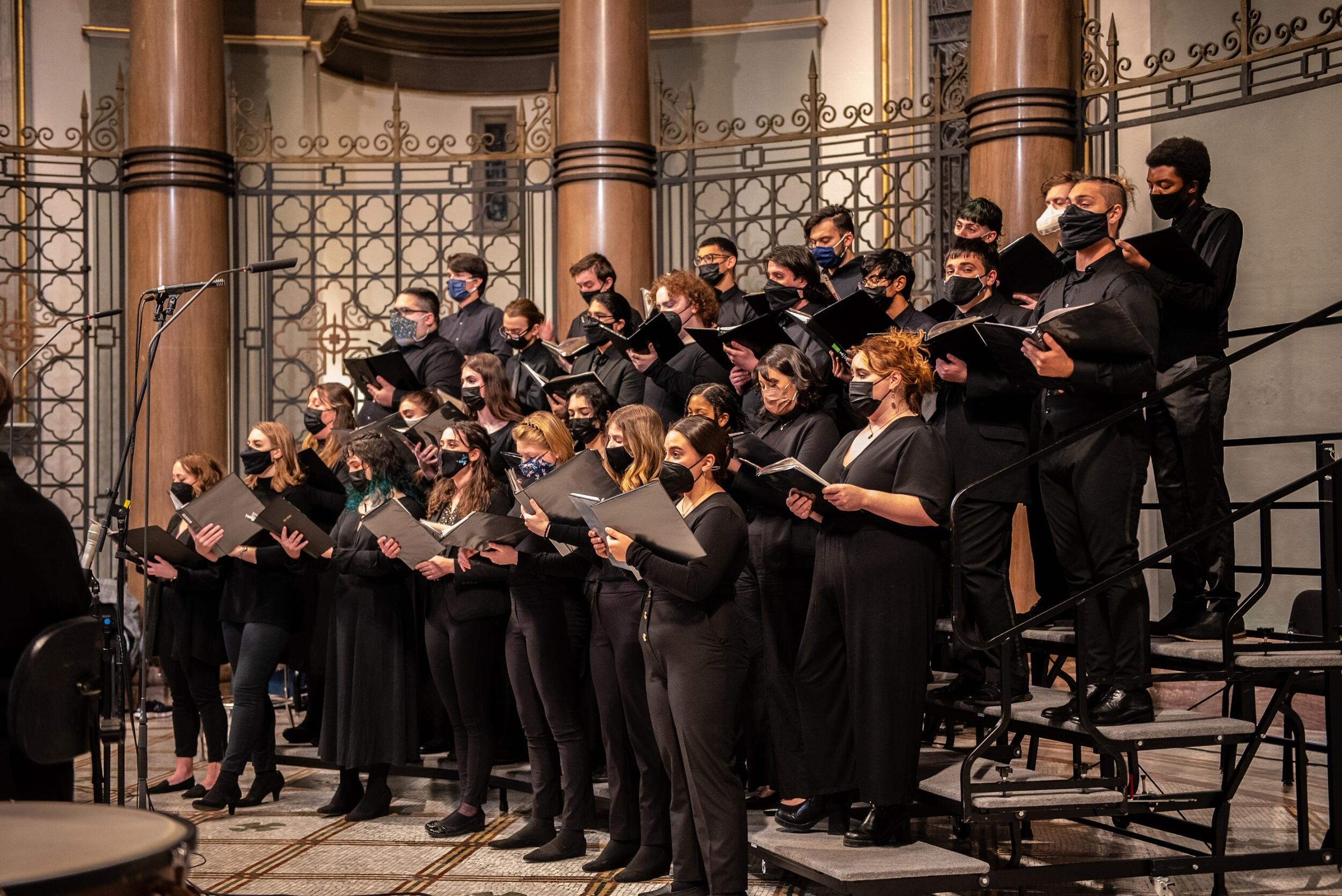 The VCU Commonwealth Singers standing on a platform singing 