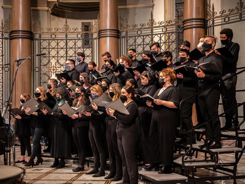 The VCU Commonwealth Singers standing on a platform singing 