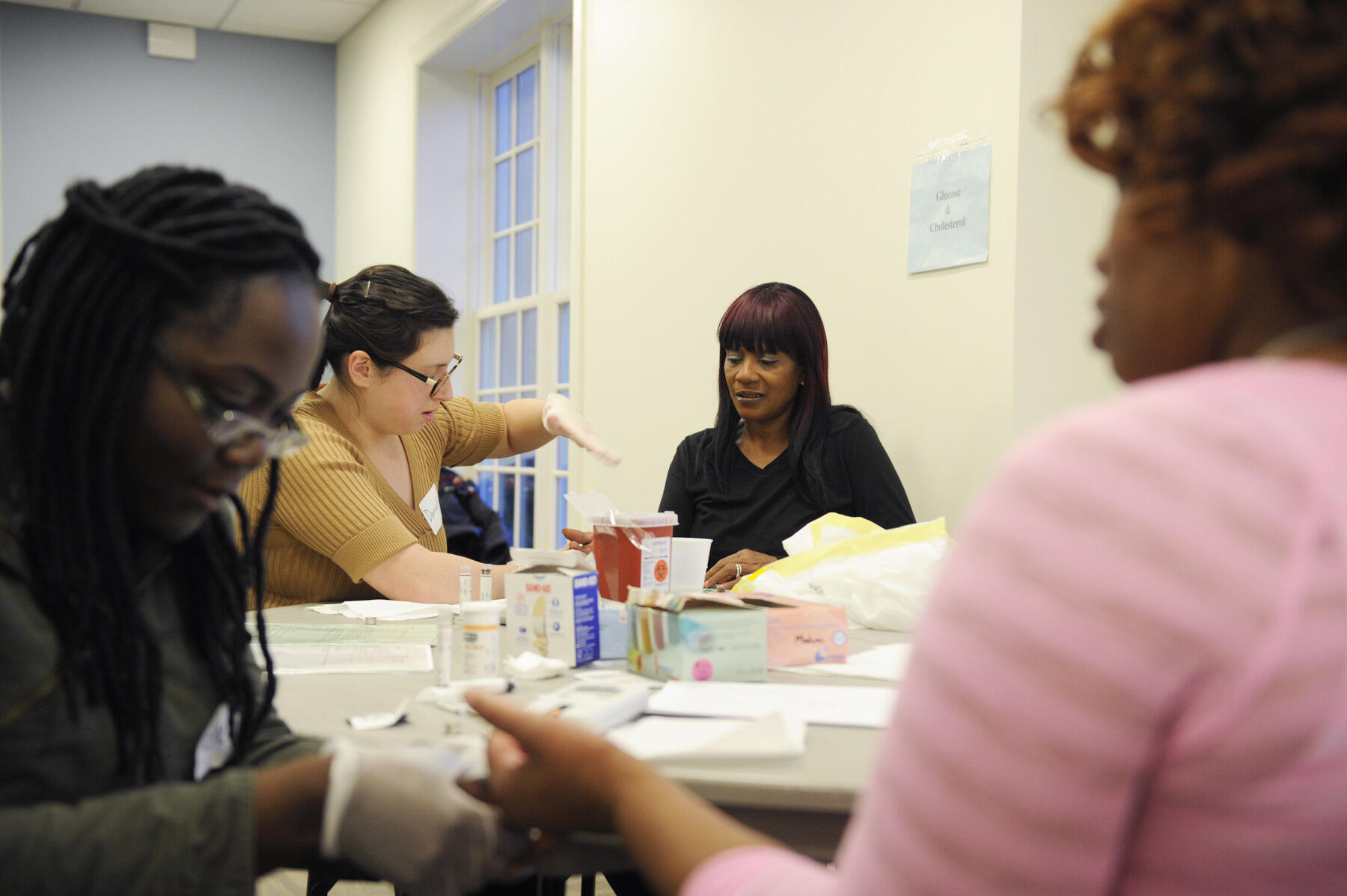 VCU medical student Danielle Austen (pictured back) checks Powell's blood sugar during the CARITAS health screening. The 23-year-old medical student wants to practice family medicine after graduating. "Preventative health is a big part of family medicine," she said. "Volunteering helps us get out there exploring how family medicine is going to be."
