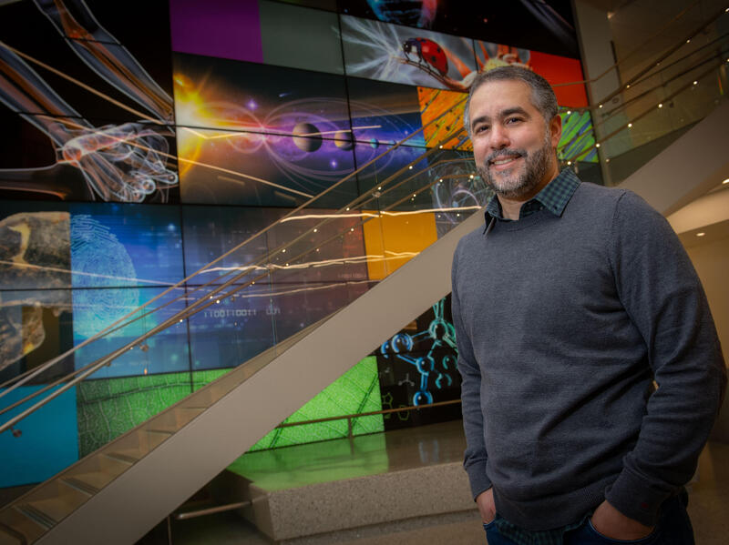 A photo of a man standing next to a staircase. 
