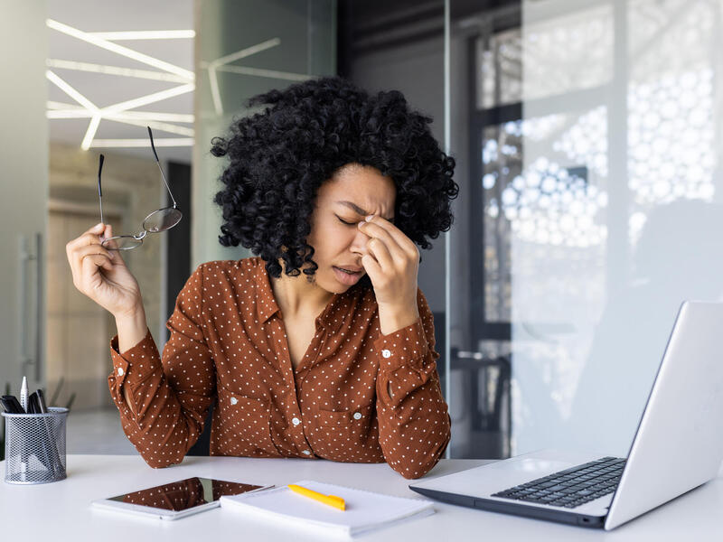A photo of a woman sitting at a desk with a laptop on it