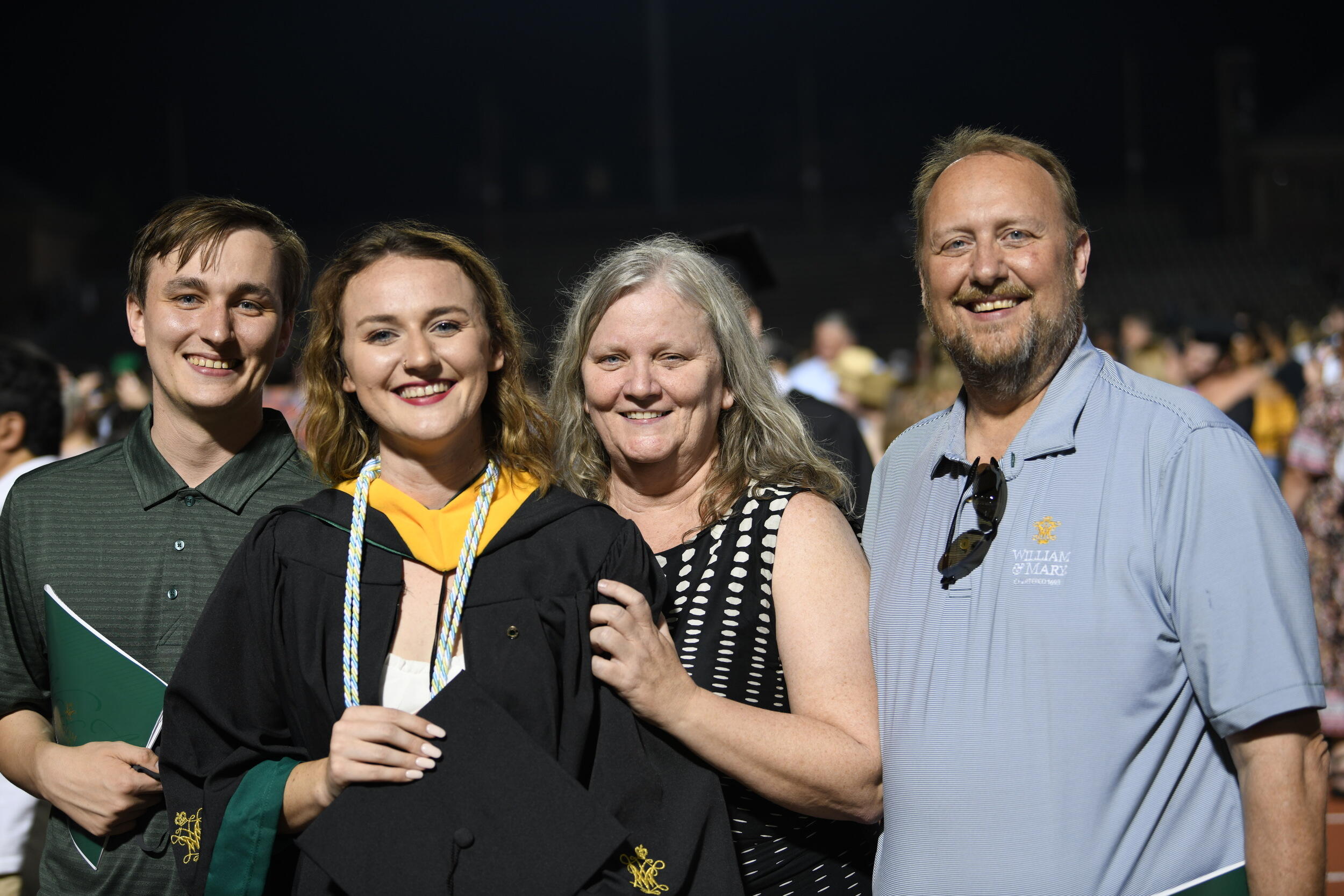 A photo of four people standing and smiling. 
