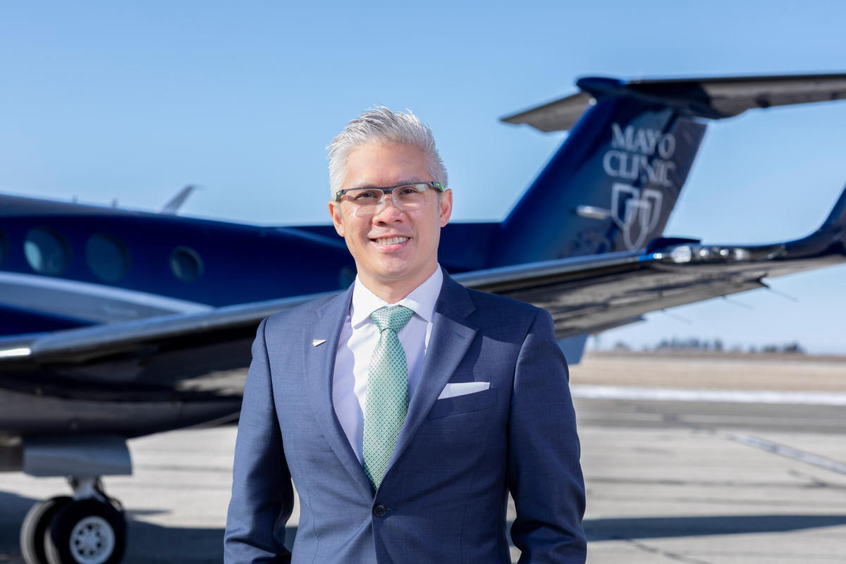 A photo of a man standing in front of a plane. 