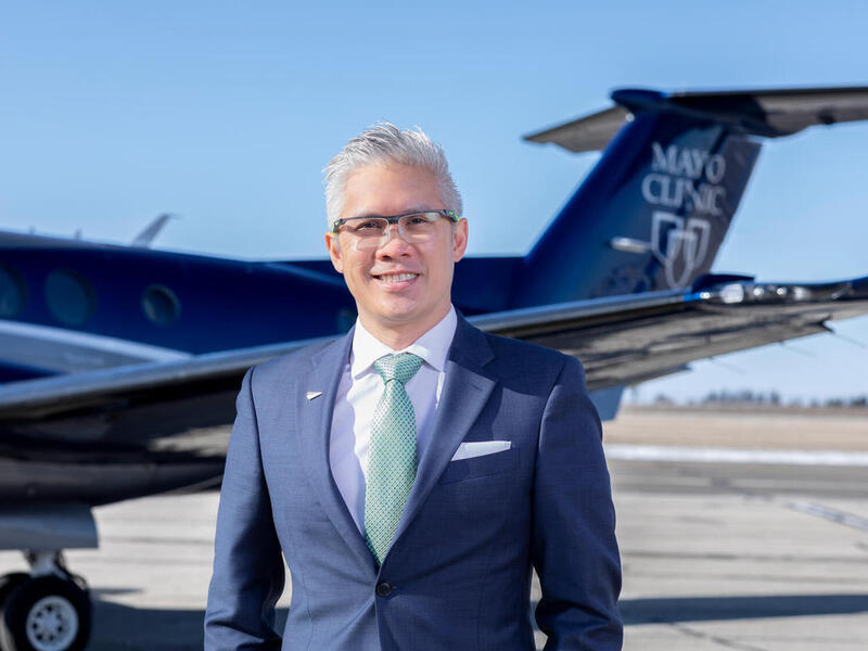 A photo of a man standing in front of a plane. 