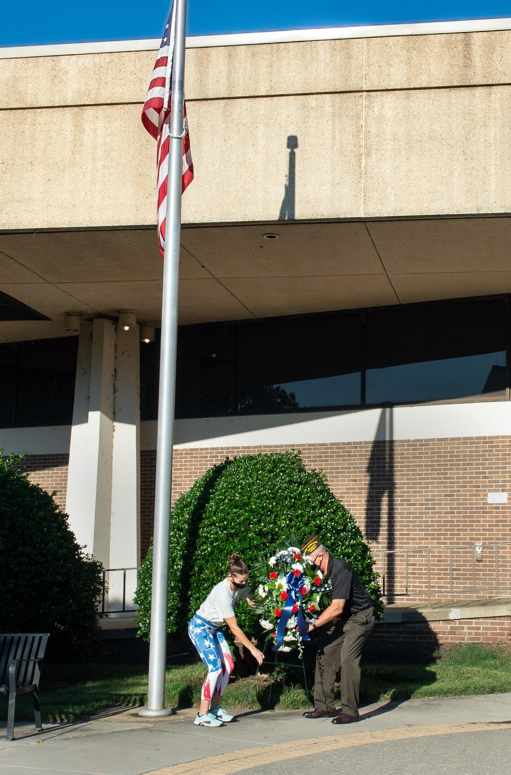 two people place a wreath in front of VCU's Harris Hall at a 9/11 anniversary event.