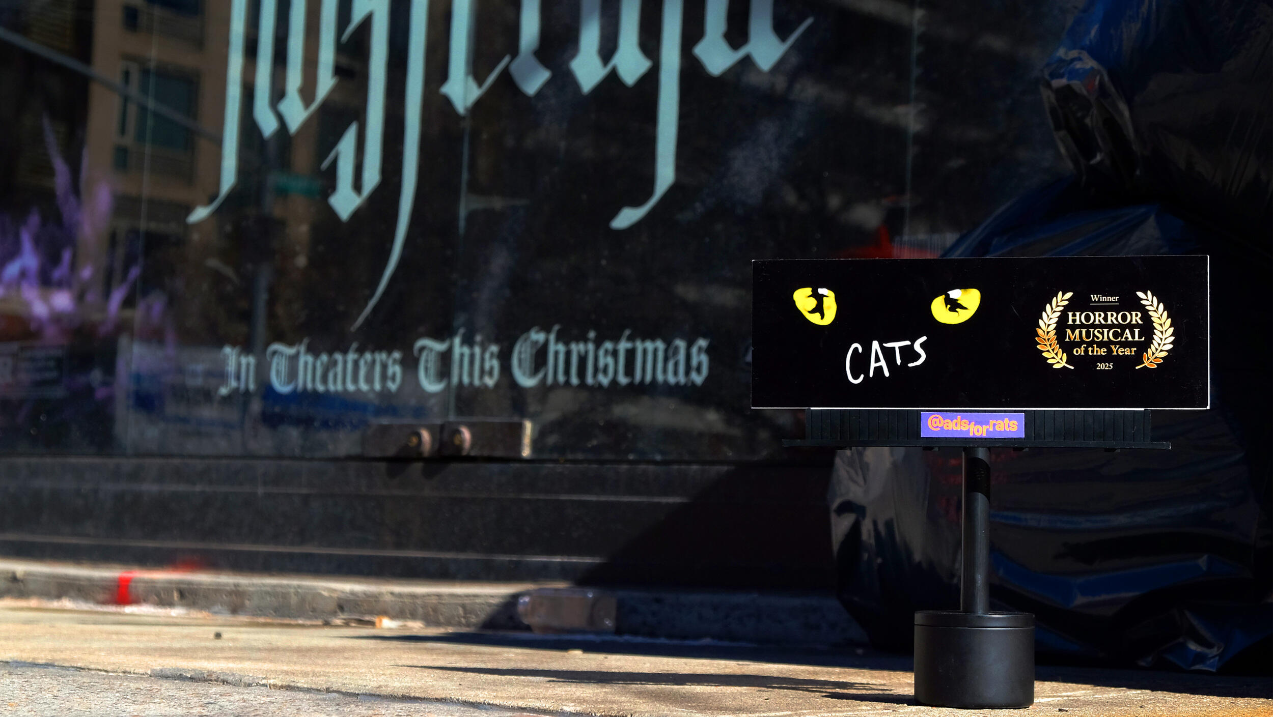 A photo of a mini billboard with the poaster for \"CATS\" the musical on it. Gold text reads \"HORROR MUSICAL of the year.\"