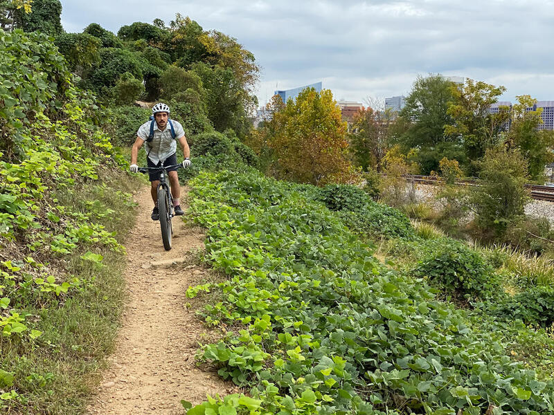A bicyclist riding on an off-road bike with the Richmond skyline in the background.