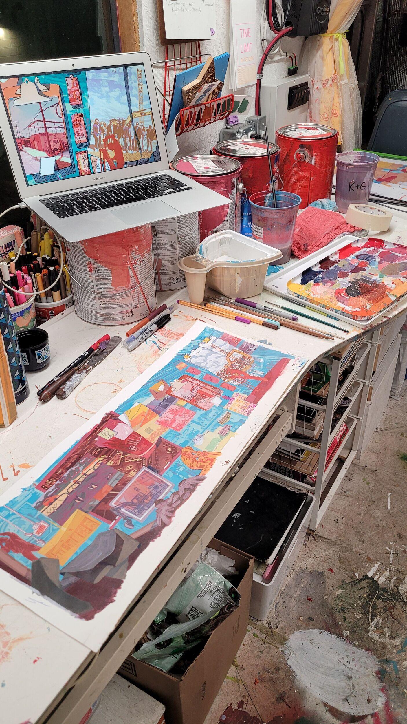 A photo of an illustration on a long sheet of paper and on a computer screen. Both are sitting on a desk. 