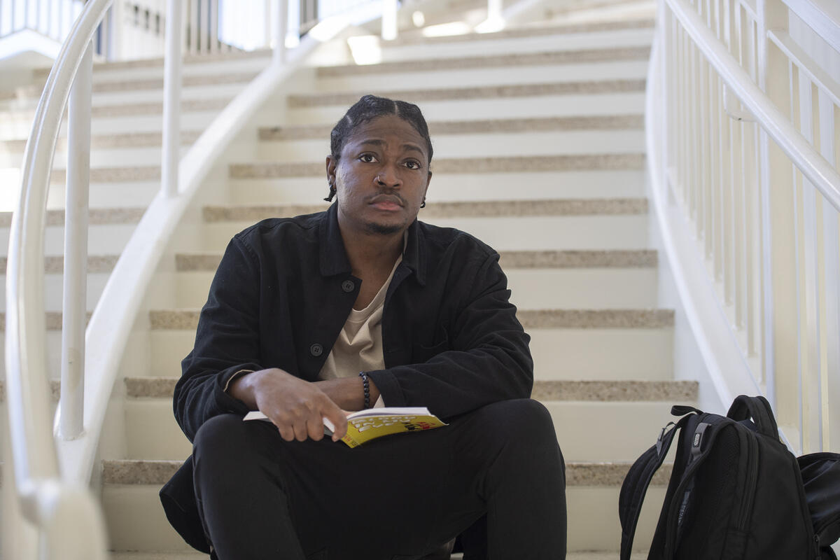 A man sitting on a staircase with a book in his lap. 