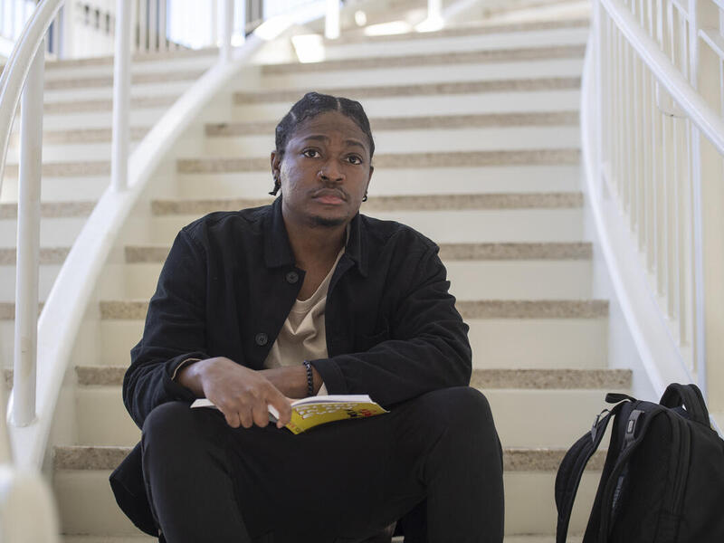 A man sitting on a staircase with a book in his lap. 
