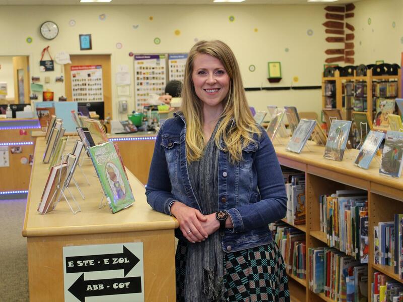 Holly Guelig leaning against a bookshelf in a grade school library 
