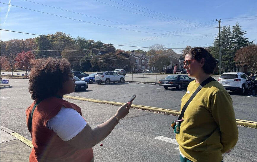 A woman holding a cell phone in front of her recording another woman speaking. 