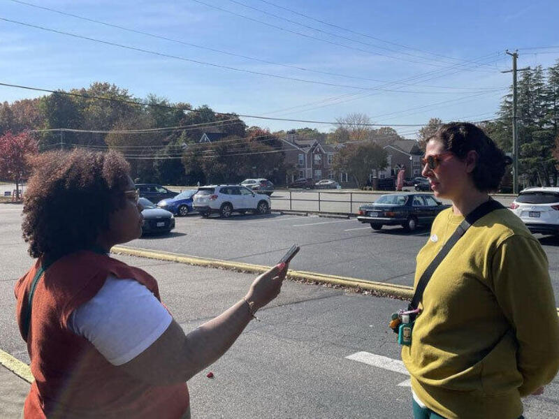 A woman holding a cell phone in front of her recording another woman speaking. 