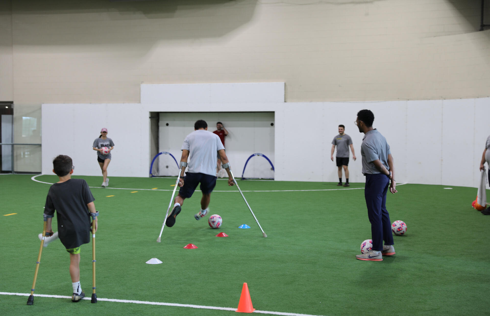 A photo of two people with mobility aids playing soccer. 