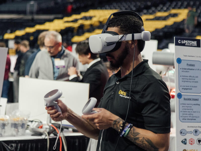 A man wearing a virtual reality headset and holding two virtual reality controllers. 