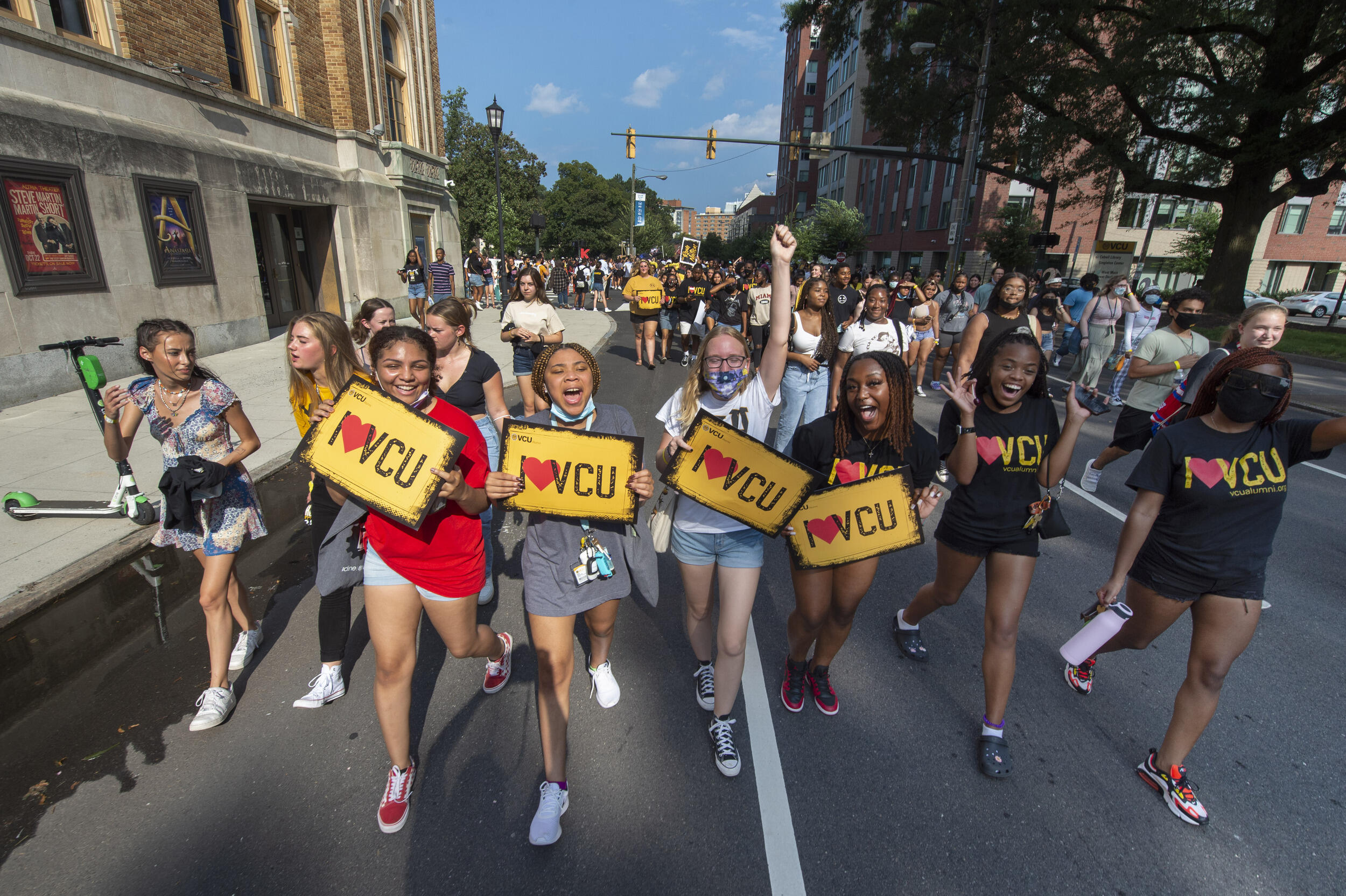 Students walking down the street holding signs that say \"I heart VCU.\"